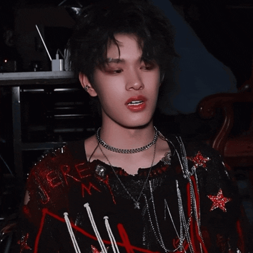 a young man wearing a choker and a sweater that says there
