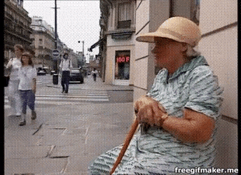 an elderly woman is sitting on the sidewalk with a cane and a hat on ..