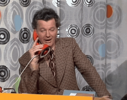 a man in a brown suit is talking on an orange phone