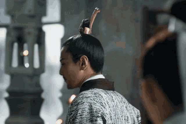 a man with a stick in his hair is standing next to another man .