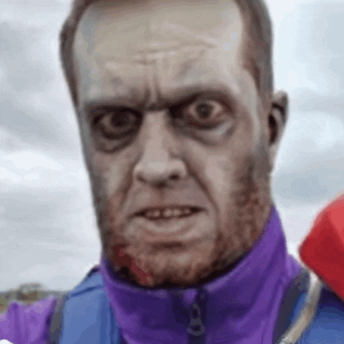 a man with a beard wearing a purple jacket is making a funny face with his eyes closed .