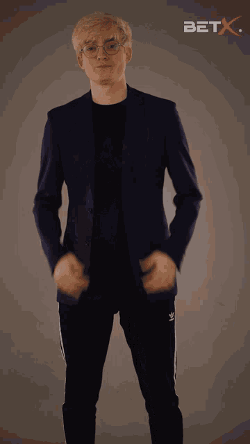 a man in a suit stands in front of a bet x logo