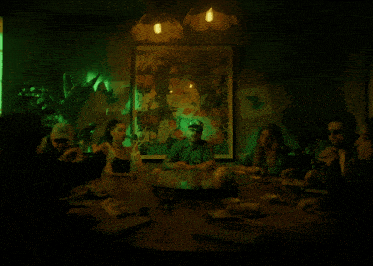 a group of people are sitting around a table in front of a green light