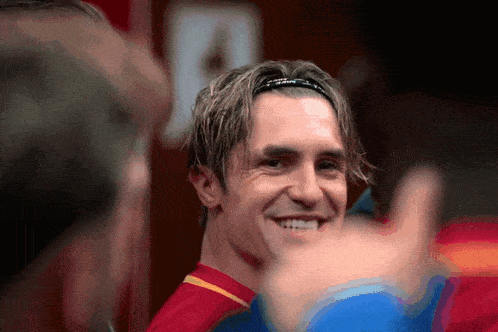 a man wearing a headband and a red shirt is smiling