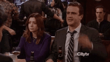 a man in a suit and tie is sitting at a table with a woman in a purple sweater .