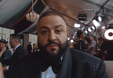 a man with a beard wearing a tuxedo stands in front of a crowd of people