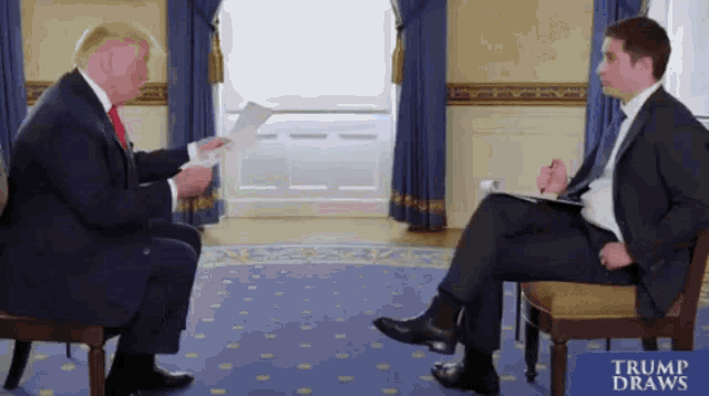 a man in a suit and tie is talking to another man in a chair with a sign that says trump draws on it
