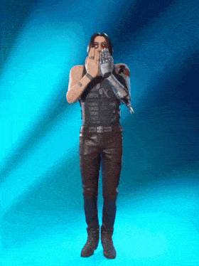 a man in a leather outfit is covering his mouth with his hand