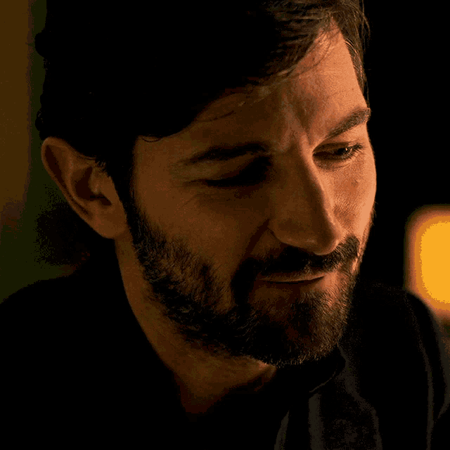 a man with a beard is looking down with a tear running down his cheek