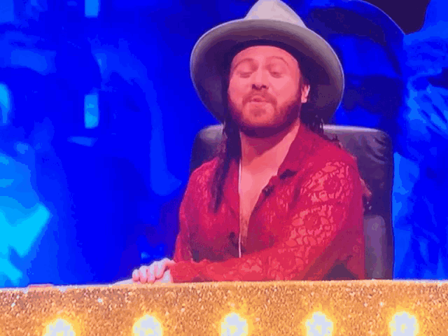 a man with a beard wearing a cowboy hat and red shirt
