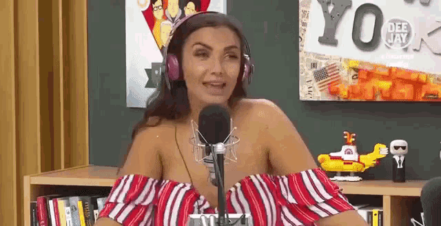 a woman wearing headphones is sitting in front of a microphone in a room .