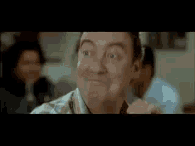 a bald man in a white shirt is smiling in a room .