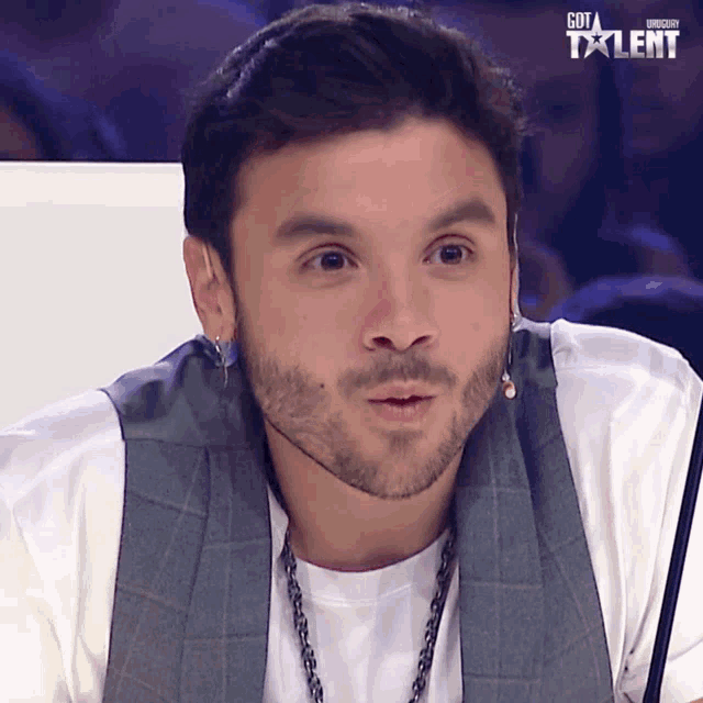 a man with a beard is sitting in front of a microphone with the words got talent on the bottom