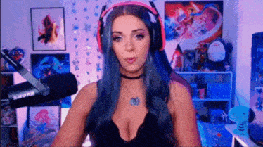 a woman with blue hair is sitting in front of a microphone wearing headphones .