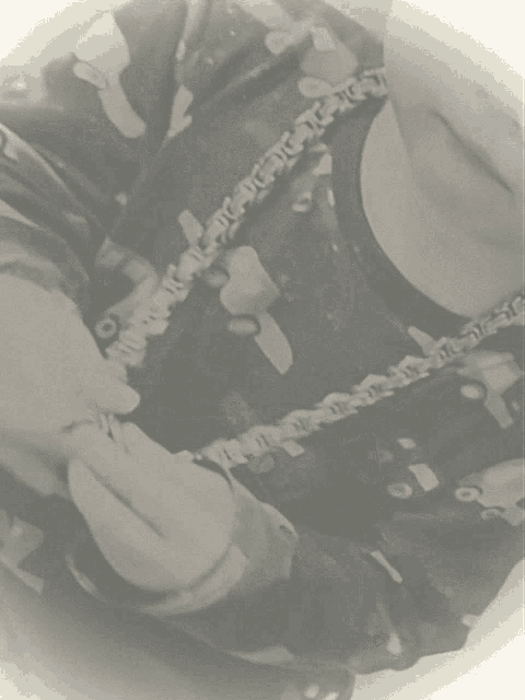 a black and white photo of a person holding a chain with the letters tc on it