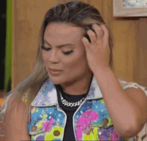 a woman in a colorful vest is holding her hair