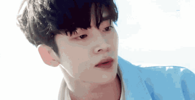 a close up of a young man wearing a blue jacket and white shirt