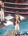 a boy is singing into a microphone on a stage while a man stands behind him .