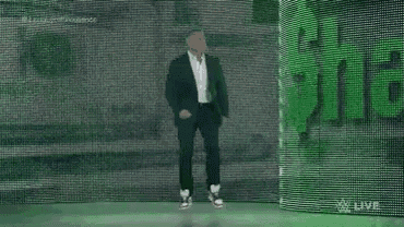 a man in a suit and white shirt is dancing on a stage in front of a green wall .