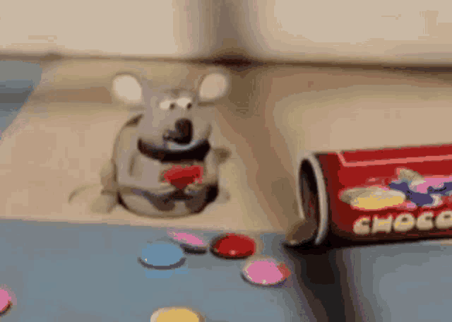 a toy mouse is sitting in a hole next to a can of choco