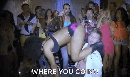 a woman in lingerie is dancing on a man 's shoulders in front of a crowd at a party .