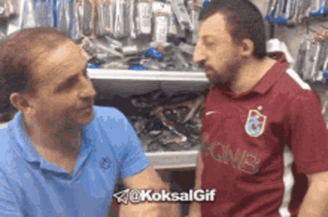 two men are talking in a store and one of them is wearing a shirt that says qnb