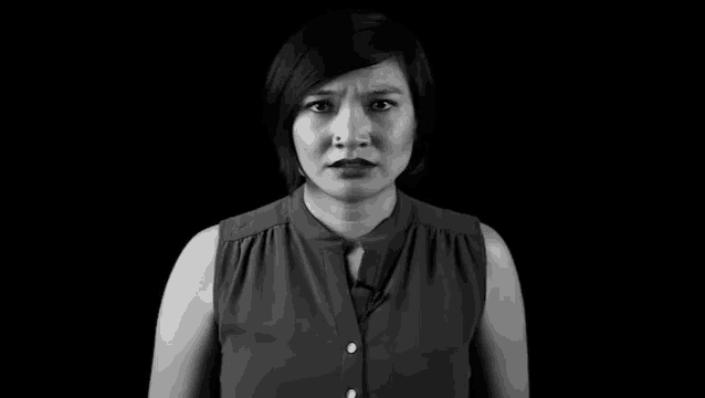 a woman is standing in front of a black background with the word death written on her chest .