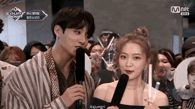 a man and a woman are standing next to each other talking into microphones .