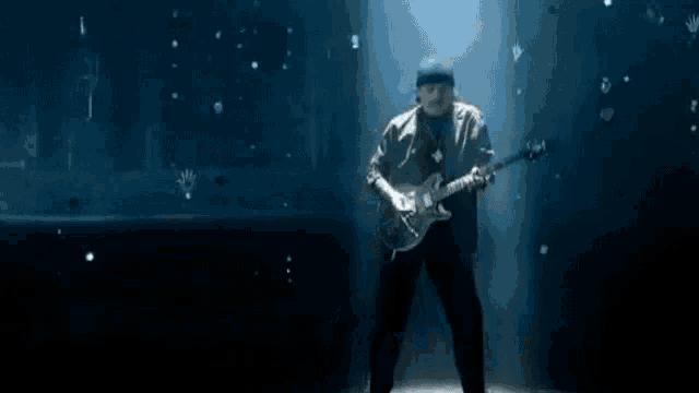 a man is playing a guitar on a stage in a dark room .