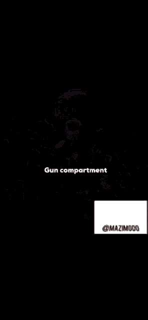 a man in a suit stands on a stage in front of a crowd with the words gun compartment written below him