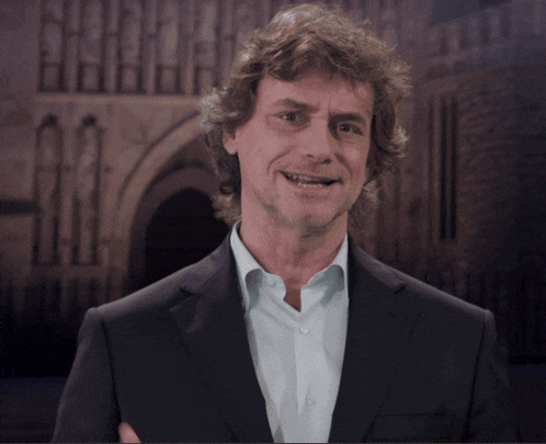 a man with curly hair wearing a suit and white shirt