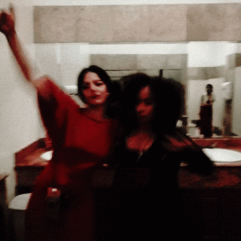 two women are standing next to each other in a bathroom .