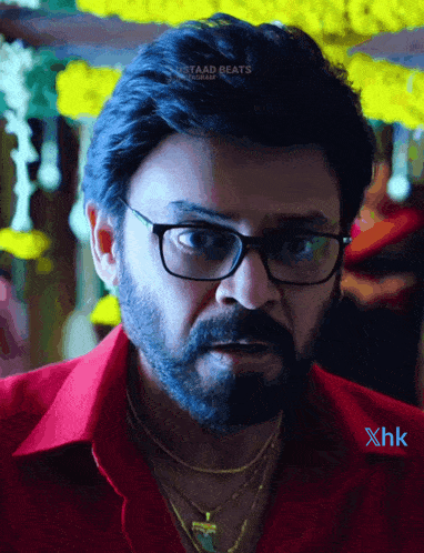 a man wearing glasses and a red shirt has the hashtag staad beats on his shoulder