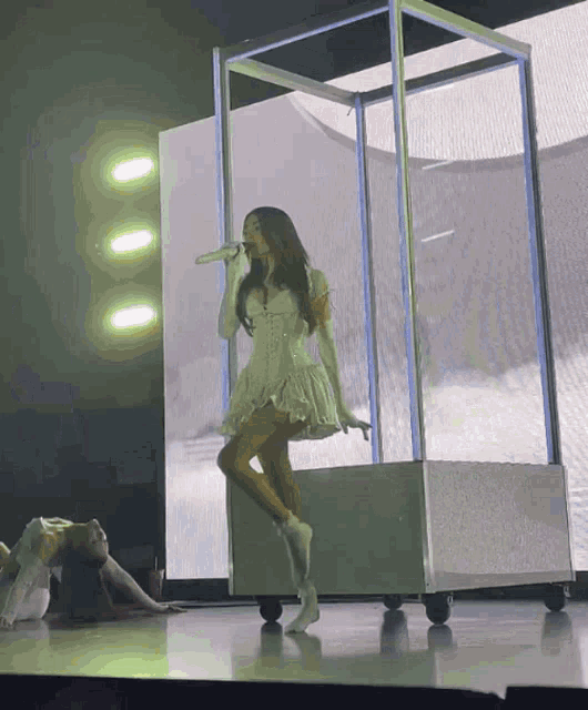 a woman in a white dress singing into a microphone on a stage