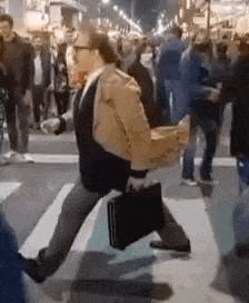 a man is carrying a briefcase while walking across a street .