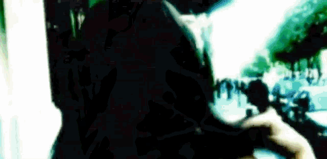 a blurry picture of a person standing in front of a crowd of people in a dark room .