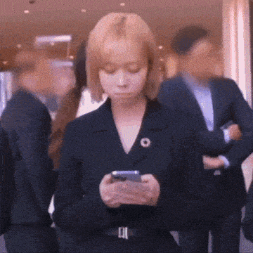 a woman in a suit is looking at her cell phone