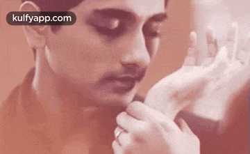 a man is kissing a woman 's hand on his cheek .