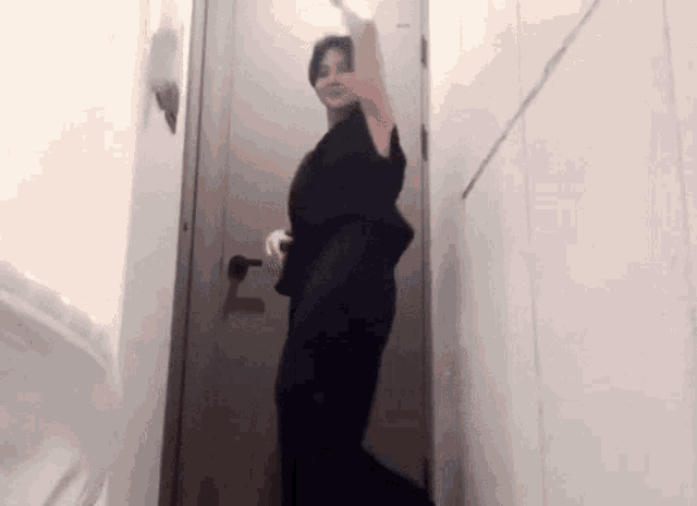 a woman in a black dress is standing in front of a door .