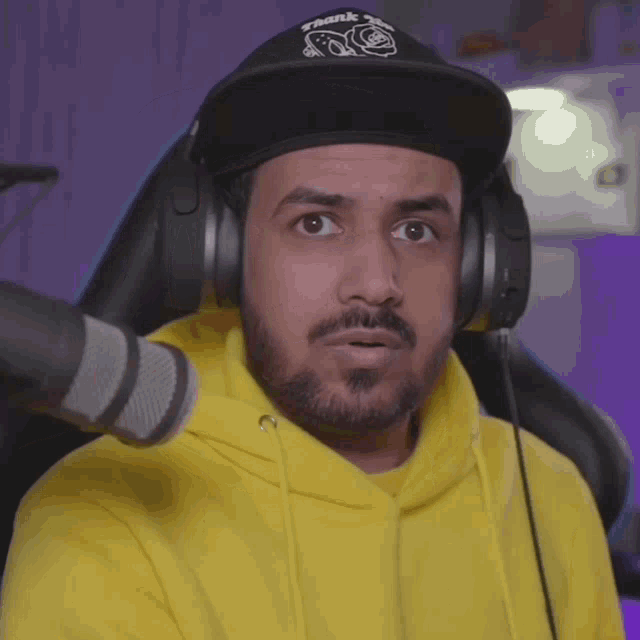 a man wearing a yellow hoodie and a black hat with thank you on it