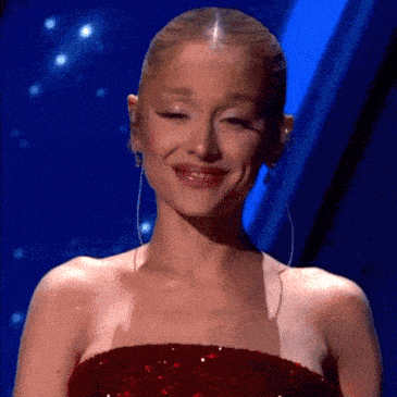 ariana grande is wearing a red sequined dress and earrings and smiling .