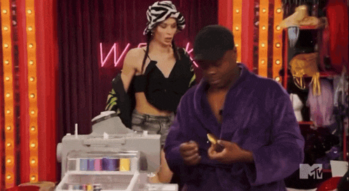 a man in a purple robe stands next to a woman in a black top and a sign that says mtv
