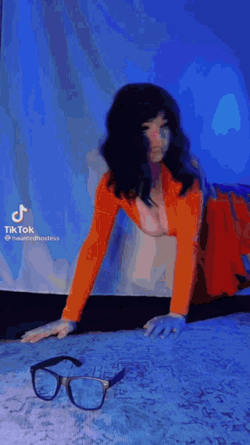 a woman in a scooby doo costume is kneeling down on the floor next to a pair of glasses .