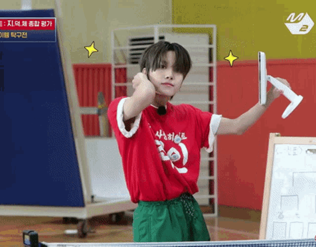 a boy in a red shirt is holding a racket in his hand