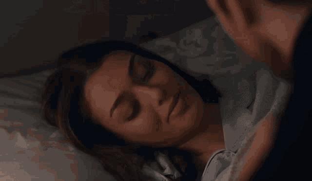 a man sits on a bed next to a woman who is sleeping