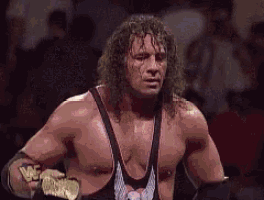 a wrestler with a skull and wings on his shirt is holding a world heavyweight championship
