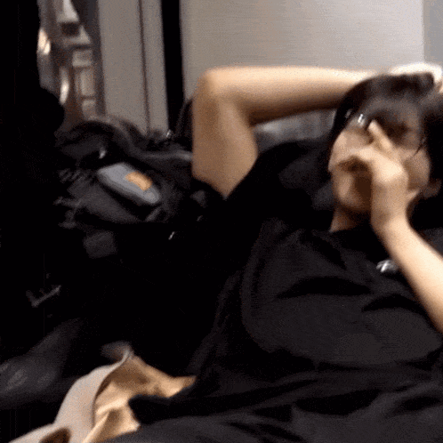 a person is sitting on a couch with their hand on their nose .
