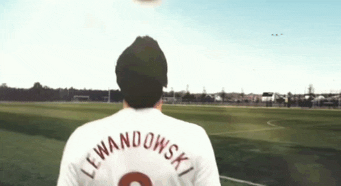 a man in a lewandowski jersey watches a soccer ball