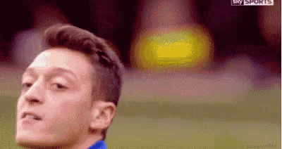 a close up of a man 's face on a soccer field with a yellow light in the background .