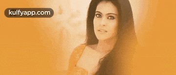 a woman with long hair is standing in front of a yellow background with the words kulfyapp.com on it .